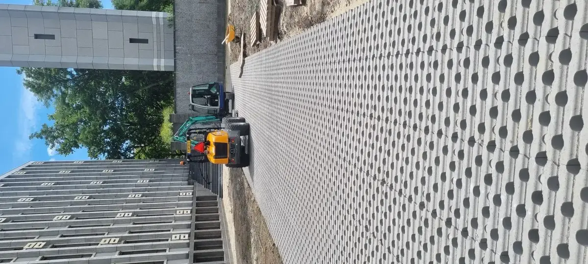 Pas gelegd vlak grasbetontegels met open cellen, met een minigraafmachine en een trilplaat op het werk