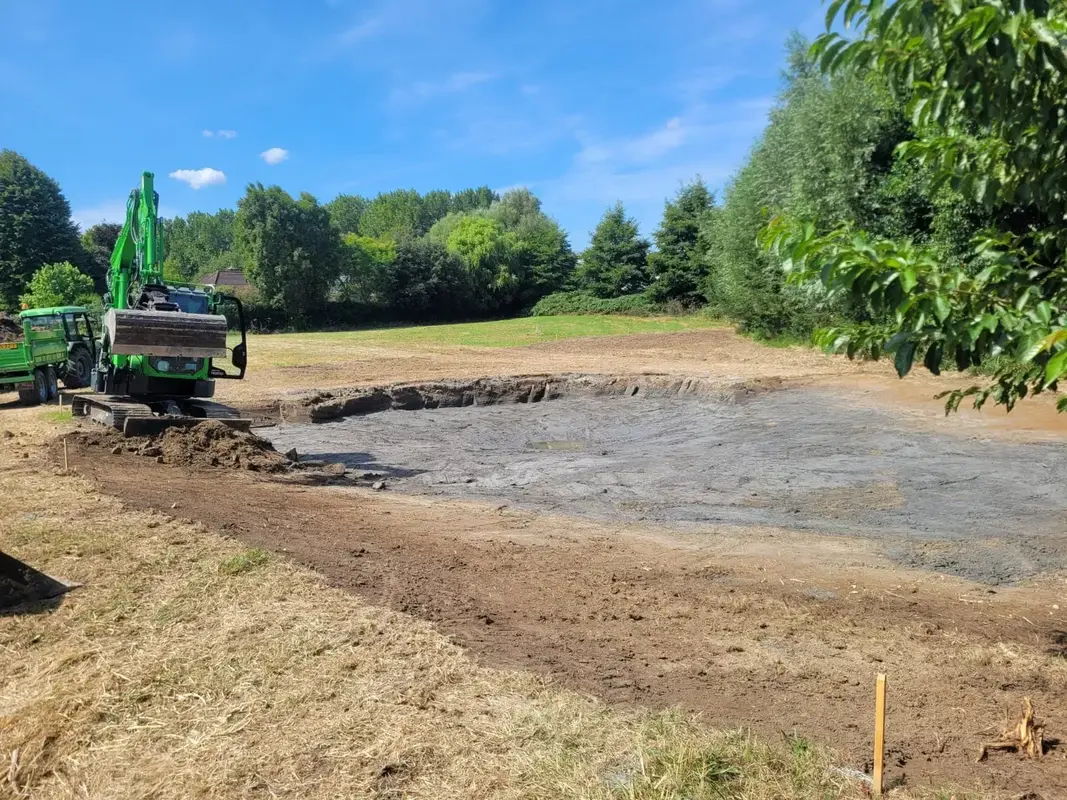 Graafmachine ontgraaft grond op een werkterrein en zet de vrijgekomen grond op depot naast de sleuf