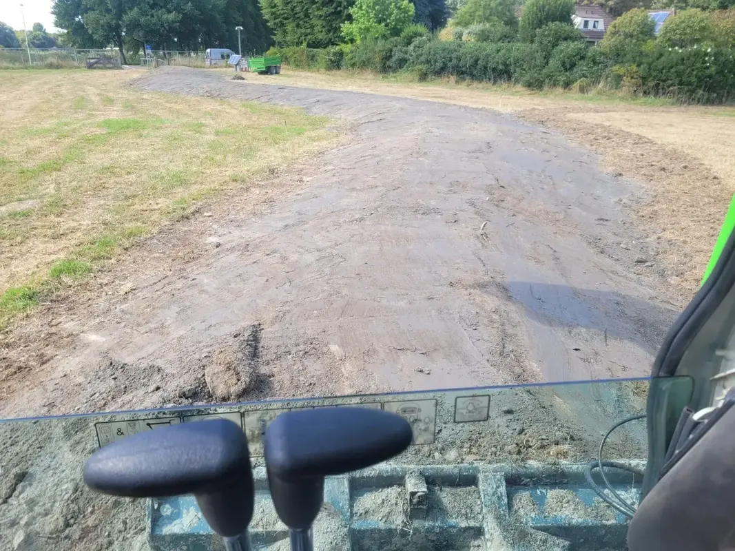 Zicht vanuit de cabine van een graafmachine op een uitgegraven en vlak geschoven baan zandgrond