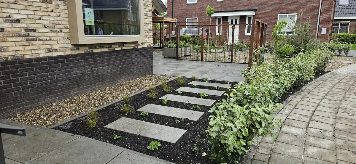 Aangelegde tuin met beplante borders en bomen die schaduw geven op een terras